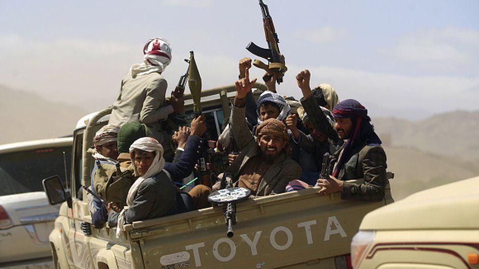 Armed Yemeni men raise their weapons as they gather near the capital Sanaa