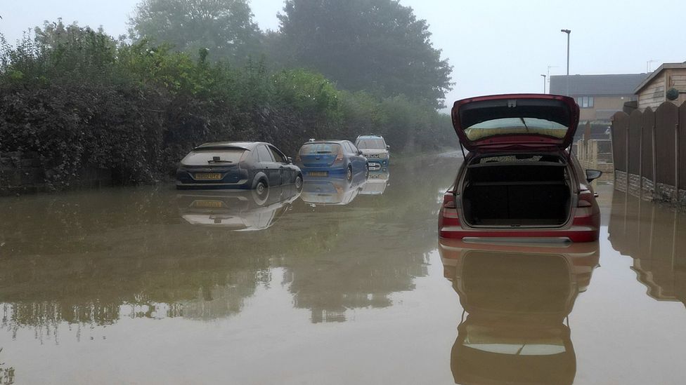 Photograph of cars with flood water high up covering the bottom part of the car.