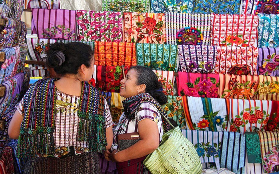 Two women looking at coloured cloth in a market
