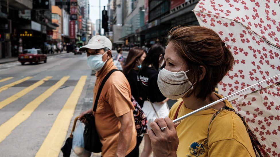 Pedestrians prepare to walk across a main road in Hong Kong on July 20, 2020.