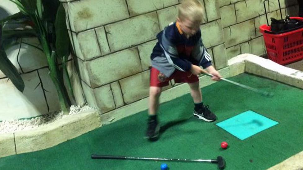 Laurence's son playing mini-golf
