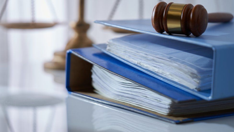 Gavel hammer on stack of document libra scale as background