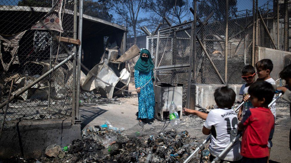 A woman stands next to destroyed shelters following a fire at the Moria camp for refugees and migrants on the island of Lesbos, Greece, 9 September 2020
