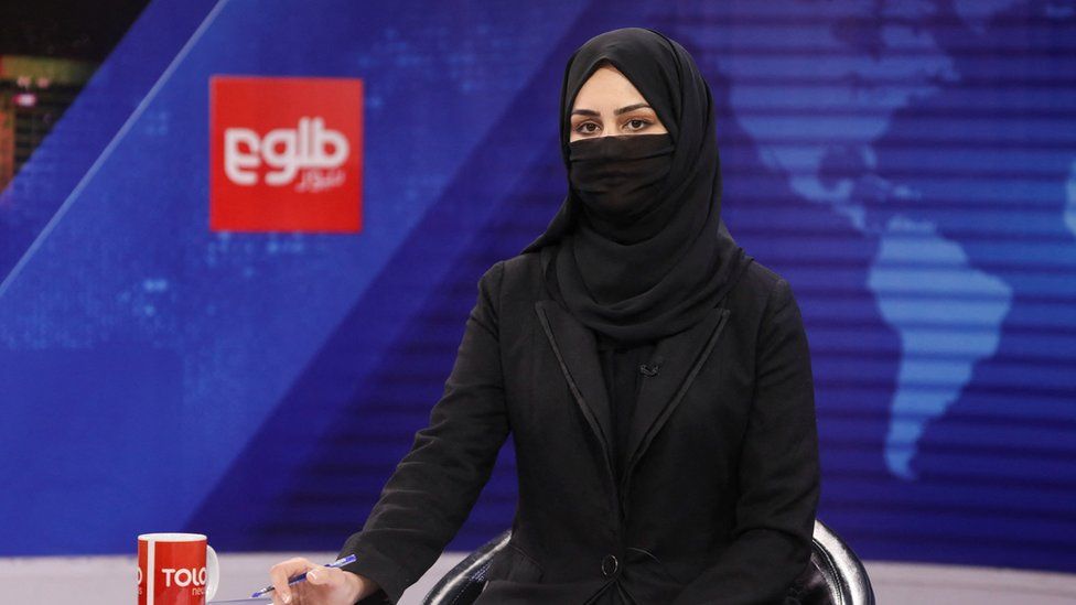 A TV presenter wearing a face covering