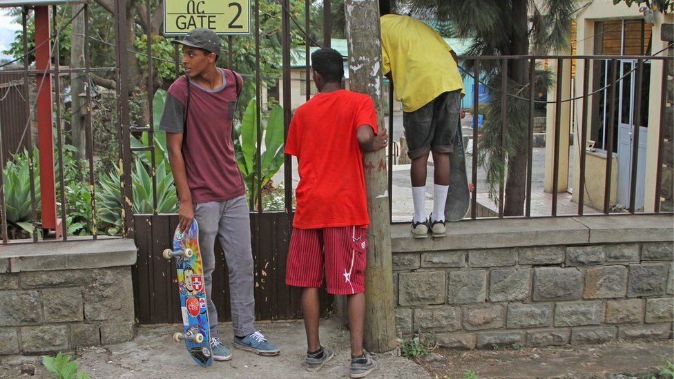 Boys peer through gate of skatepark