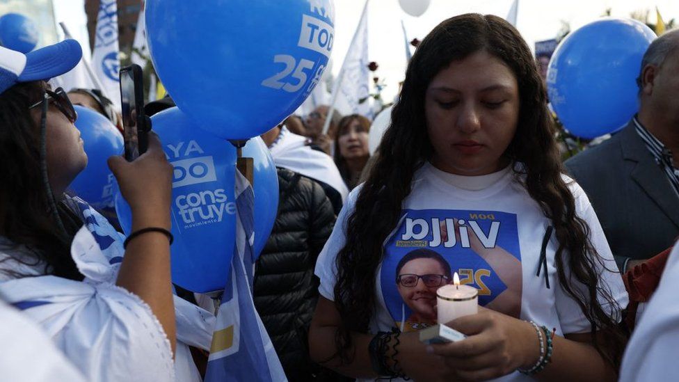 A girl holds a candle while wearing a campaign t-shirt bearing the face of Fernando Villavicencio, a presidential candidate in Ecuador who was assassinated in August 2023