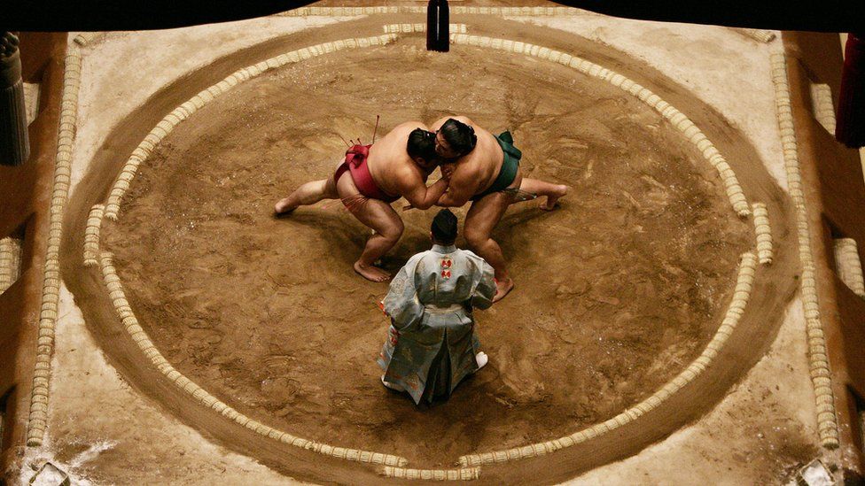 Sumo wrestlers Miyabiyama and Takekaze of Japan grapple each other in the middle of the ring during the Grand Sumo Championship
