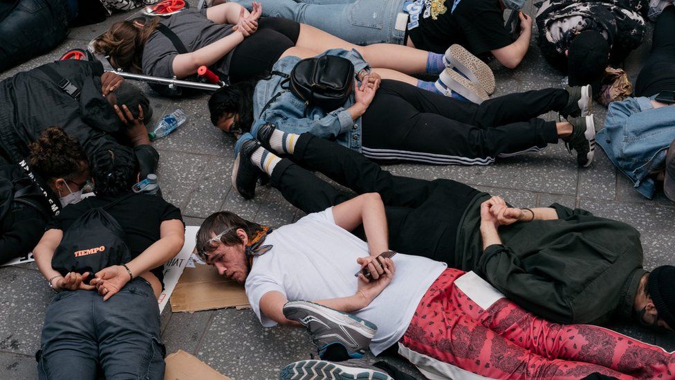 Protesters lie on the ground with their hands behind their backs