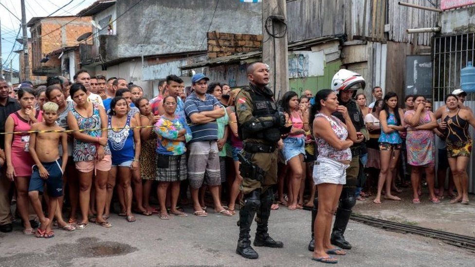Residents gather outside a bar as forensic personnel and criminal police remove corpses after a shooting, in Belem, Para state, Brazil on May 19, 2019.