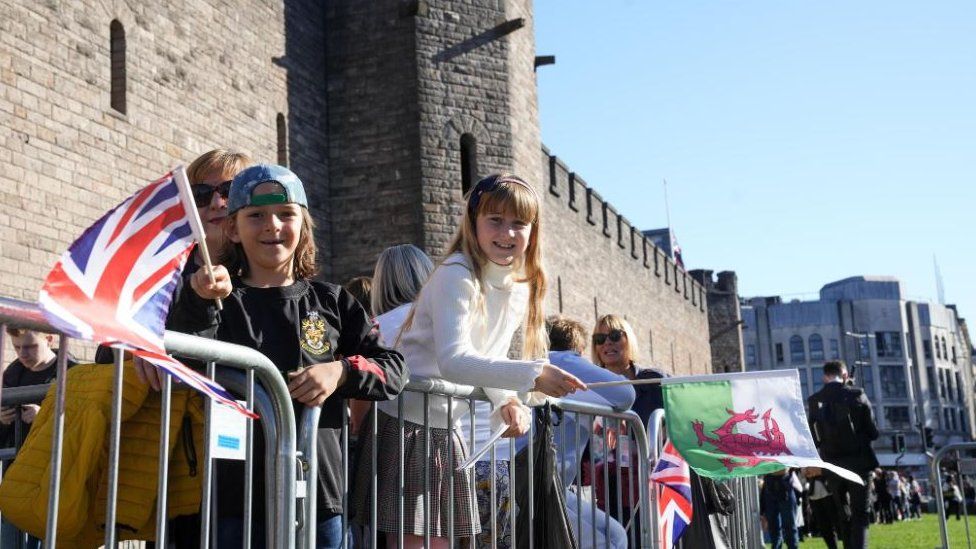 Children wait in line holding flags to see the King