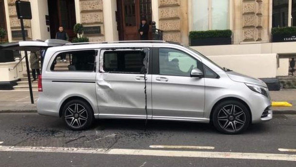 A grey taxi badly damaged with smashed windows outside the Clermont hotel on Buckingham Palace Road