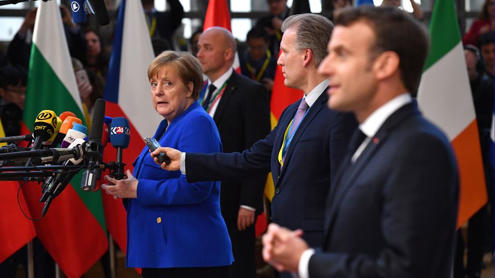 Germany's Chancellor Angela Merkel looks back at French President Emmanuel Macron as they speak to the media