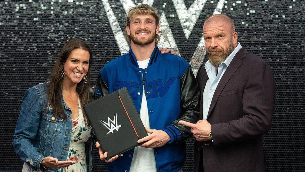 Logan Paul stands with Stephanie McMahon and her husband Triple H