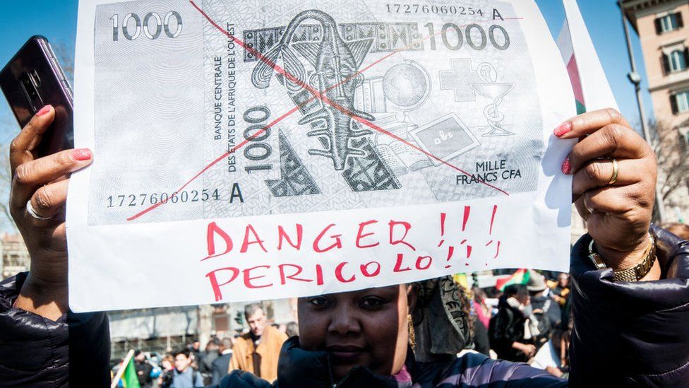 A woman holding a printout of a franc note during protests in Rome in 2019