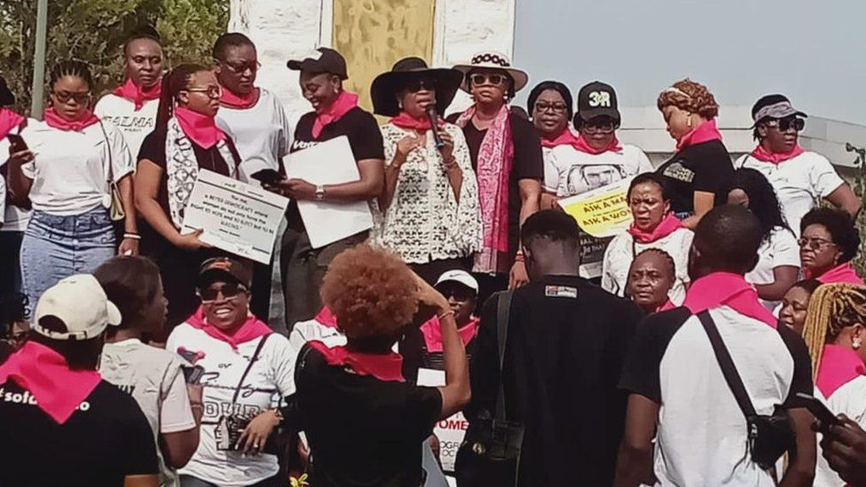 Женщины в розовых шарфах протестуют у здания правительства Нигерии.