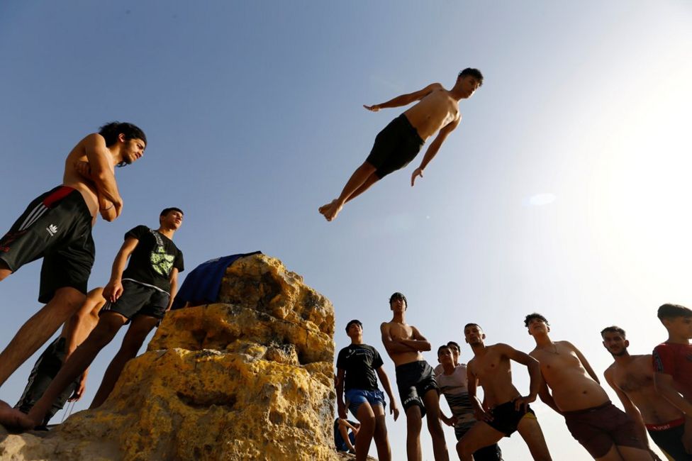 A crowd of people watch a boy diving