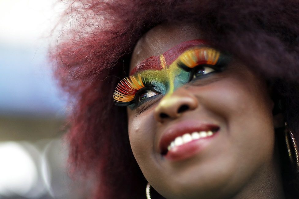 A smiling woman wears false eyelashes and the colours of the Senegalese flag in face paint at an Under-20 World Cup football match against Colombia in La Plata, Argentina - Saturday 27 May 2023