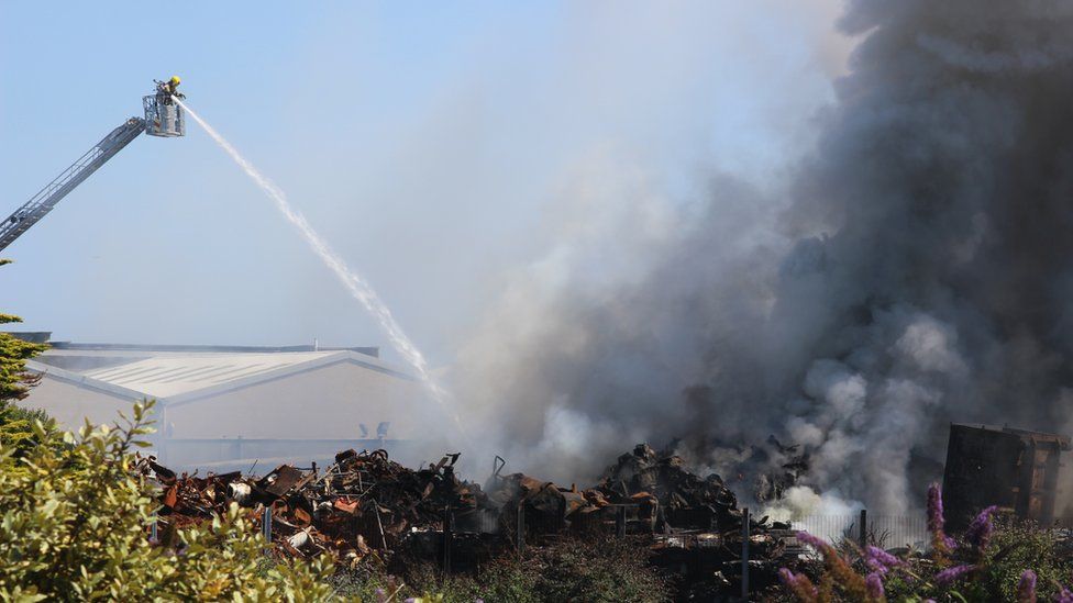 Firefighter using hose from turntable ladder to tackle Guernsey Recycling blaze