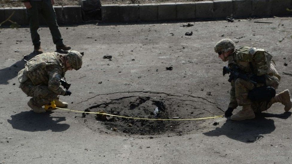 Nato soldiers measure a crater at the site of a suicide car bomb attack that targeted foreign military vehicles in Kabul (11 October 2015)