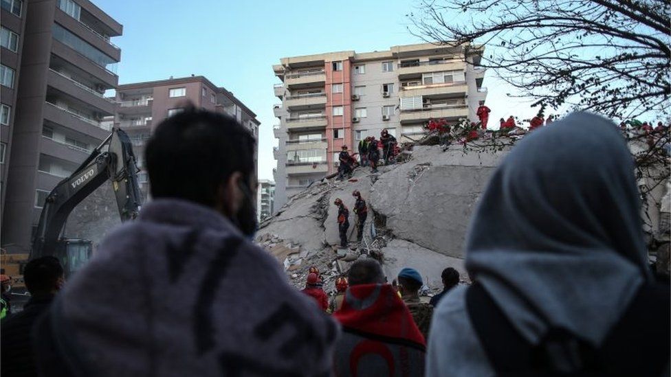 People stay near a collapsed building and wait for news from their relatives believed to be trapped under collapsed buildings after a 7.0 magnitude earthquake in the Aegean Sea; at Bayrakli district in Izmir, Turkey, 31 October 2020