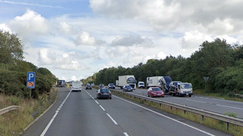 Dual carriageway with lorries and cars, and a P sign indicating a layby to the left