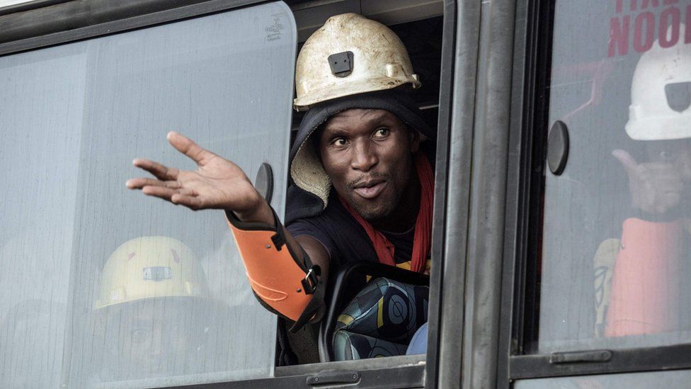 A rescued South African miner gestures out a bus window, 2 February 2018