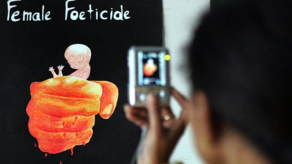 A young girl, Aman Kaur takes a photograph of paintings displayed during the opening of the art exhibition 'Female Foeticide' at Virsa Vihar hall in Amritsar on January 25, 2009.