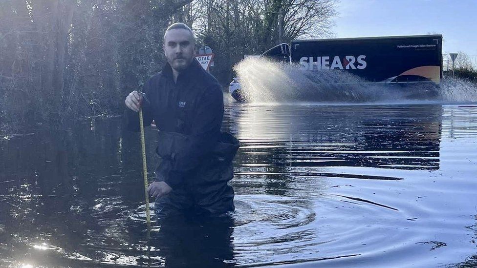 A man standing almost waist deep in floodwater