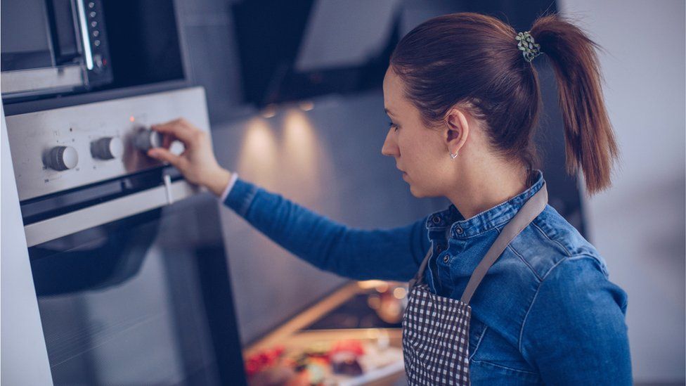 Stock image of woman using cooker
