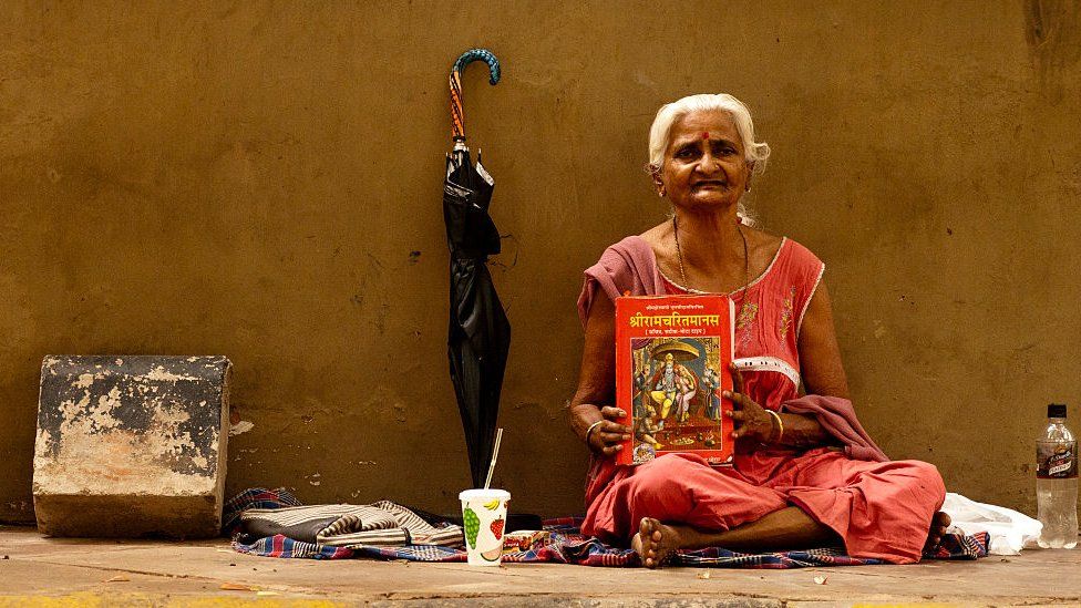 A woman sits with a copy of Ramcharitmanas