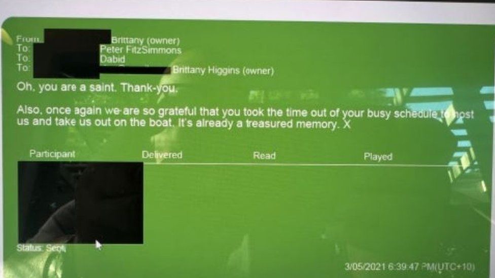A photo of a laptop screen showing a text message, with a bald man in the reflection
