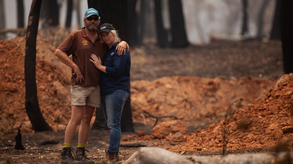 Travis and Belinda Attree cling to each other as they assess their scorched land