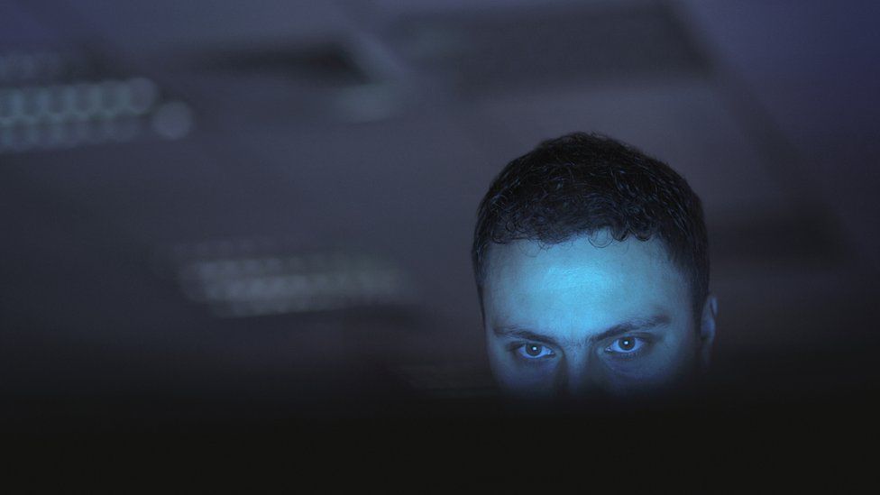 Stock image of a shadowy figure using a computer