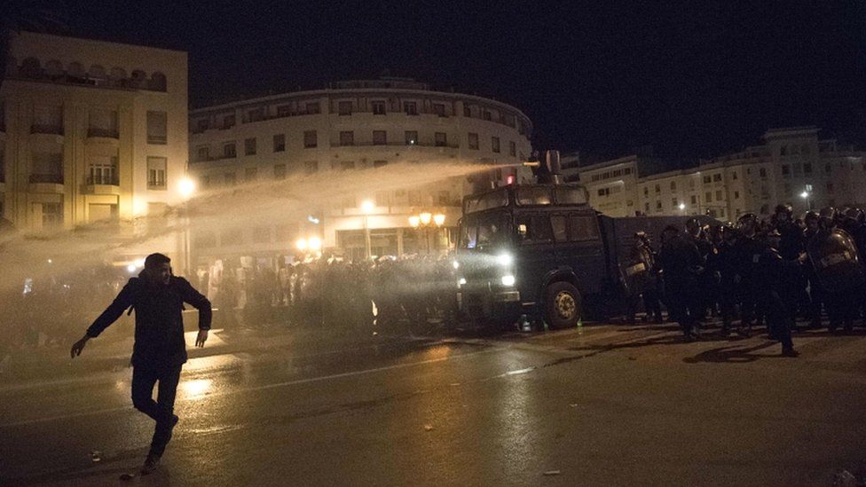 A Moroccan protester runs as the police use a water cannon during a demonstration in the capital Rabat on 24 March 2019