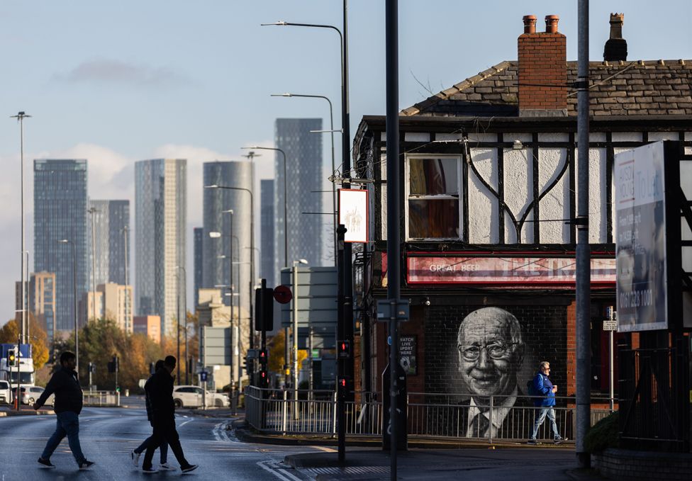 The Manchester skyline is seen behind a mural depicting the late Sir Bobby Charlton painted on the side of The Trafford pub near Old Trafford stadium in Manchester, Britain, 17 November 2023.