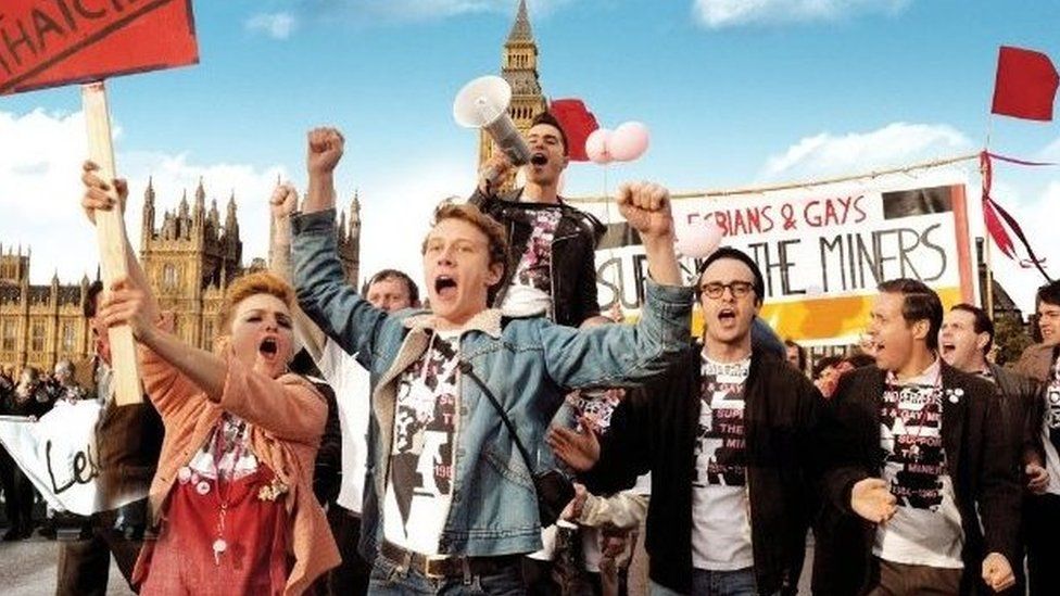 A promotional images showing the cast of the film Pride in character as the take part in a protest march in London