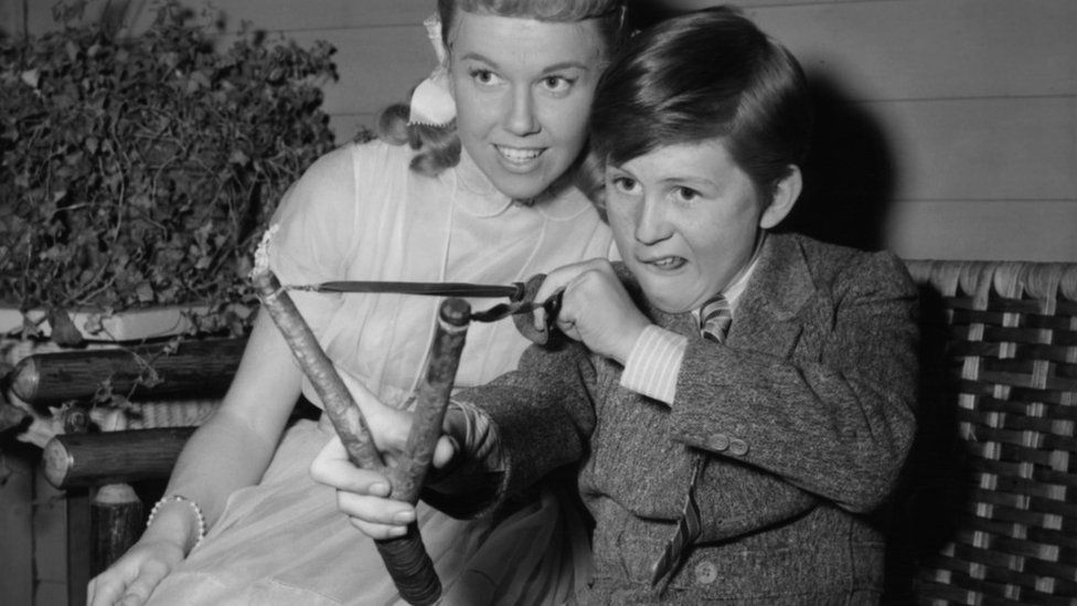 Doris Day watches Billy Gray with slingshot off-camera from the film 'On Moonlight Bay', 1951