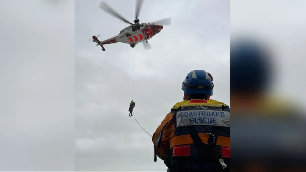 A person being winched to safety by a helicopter