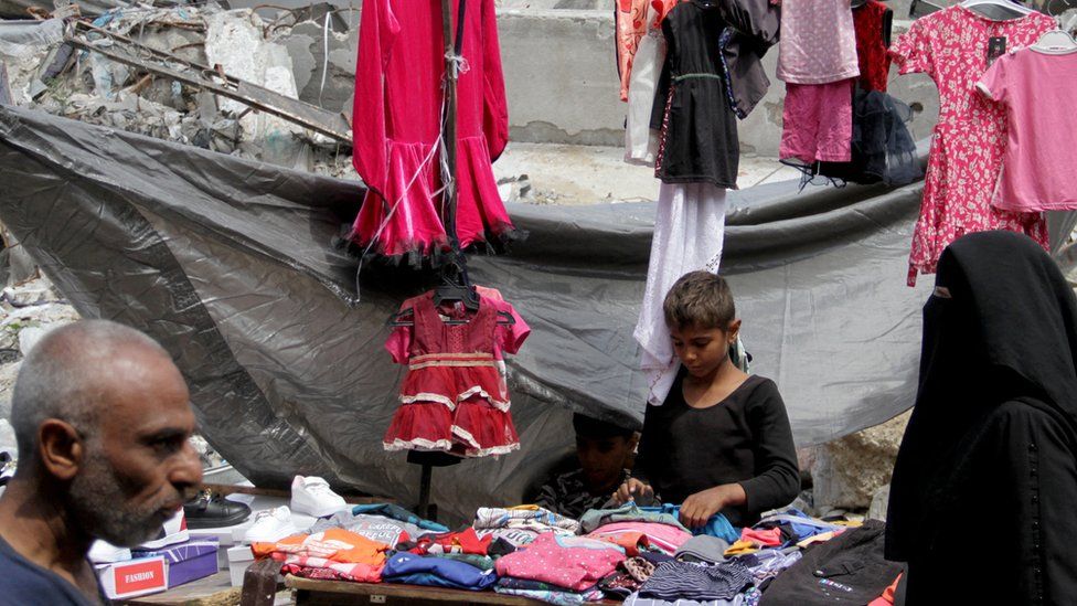A boy works at a stall selling clothing for Eid al-Fitr in the northern Gaza strip (9 April 2024)