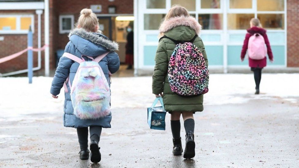 2 children walking towards a school