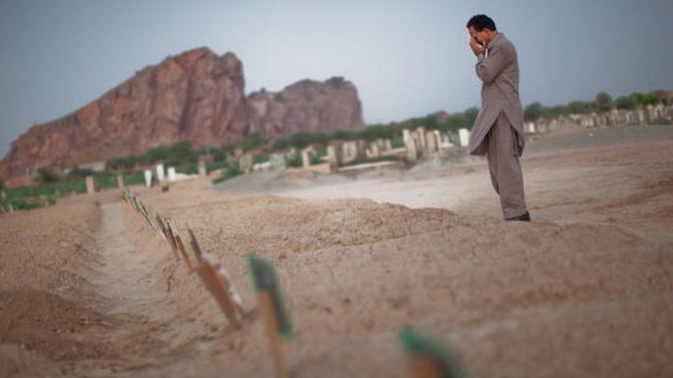 A man cries as he prays at the graves of members of the Ahmadi community after attacks on mosques in Lahore (July 2010)