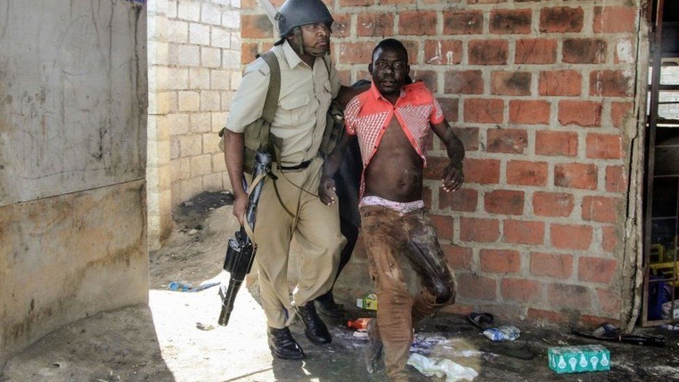 A Zambian Policeman apprehends an alleged looter in the Zingalume Compound where residents have attacked broken and looted foreign-run shops in Lusaka on April 18, 201
