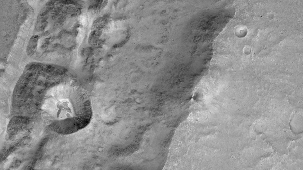 A CaSSIS image of a 1.4km sized crater (left centre) on the rim of a much larger crater near the Mars equator