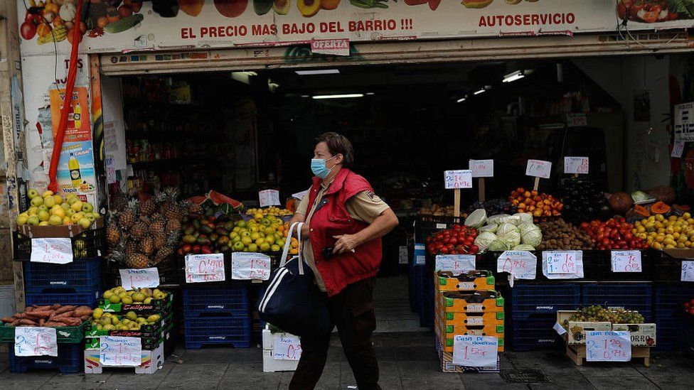 Masked shopper leaves a grocery store in Madrid on 18 September 2020