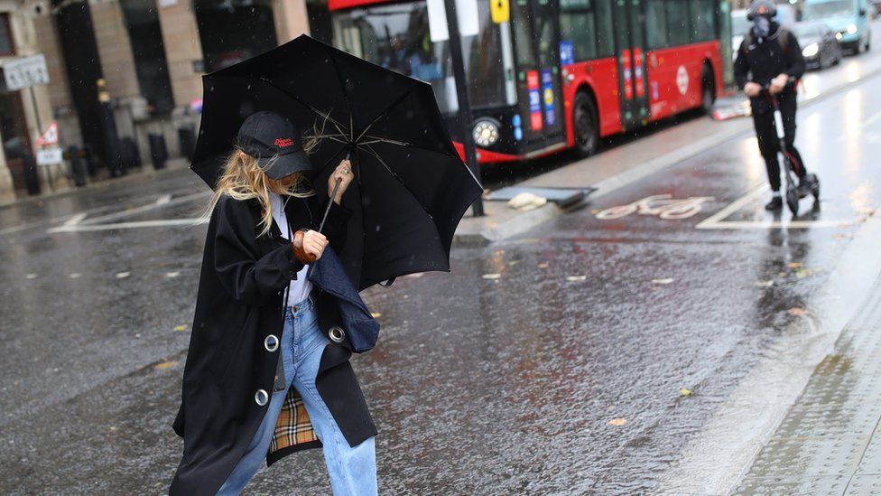 A woman walks through rain in Westminster