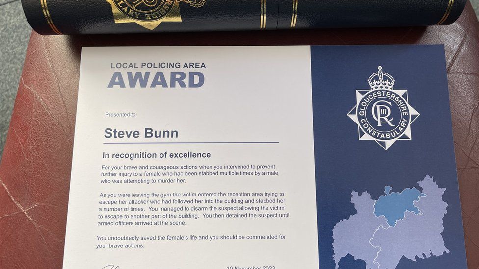 A certificate for Steve Bunn from the Gloucestershire Constabulary in recognition of excellence, written in blue on a white background, with a smart black and gold tube in the background to contain it.