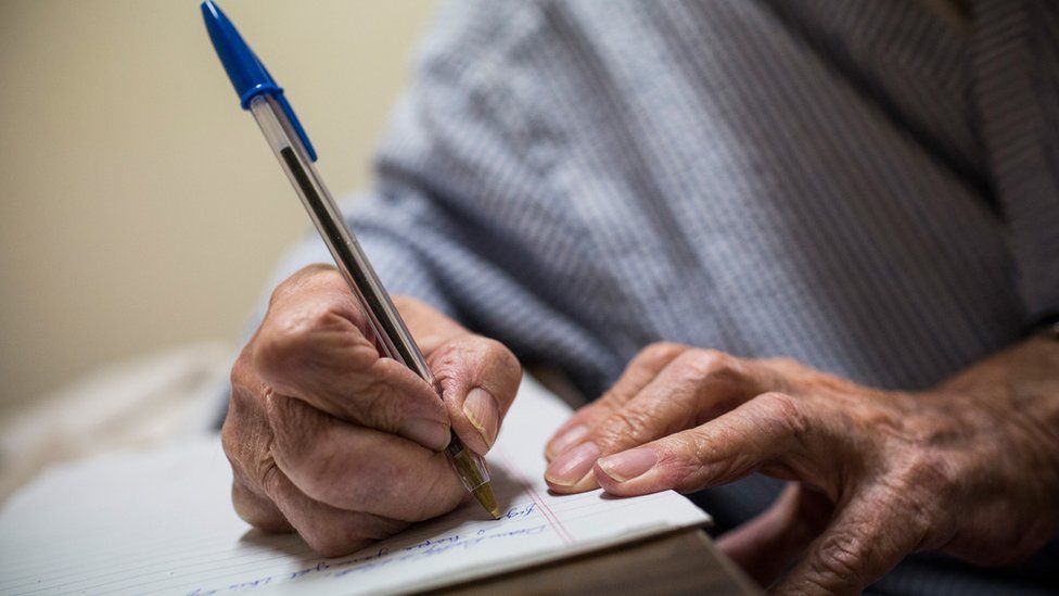 An elderly man writing, stock photo