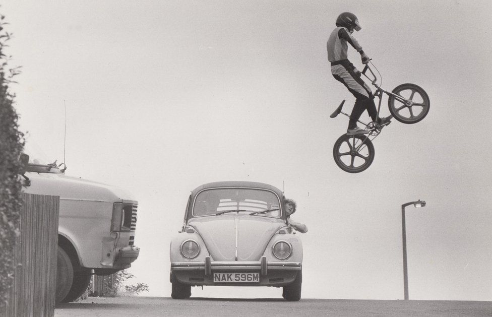 Bmx rider leaps over road with car driving down