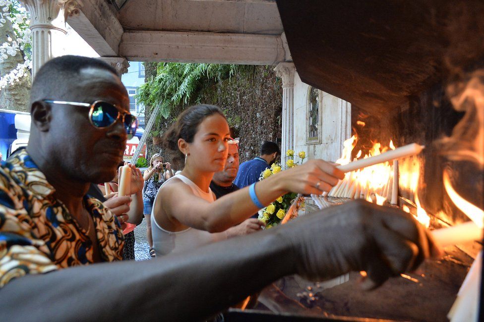 People light candles at the area affected by a tree fall that killed 13 people in Funchal, 15 August