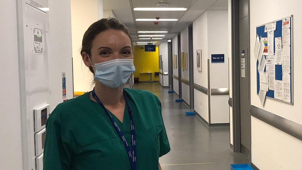 Dr Katrina Pollock in scrubs and a mask in hospital corridor